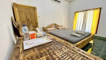 A room with a bed, a wooden table with a menu, a water bottle, and a tissue box.