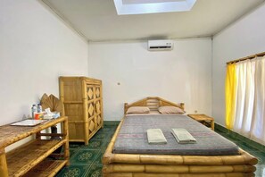 Una habitación con cama, un escritorio de madera, un armario y una ventana con cortinas.