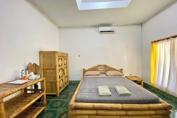 A room with a bed, a wooden desk, a wardrobe, and a window with curtains.