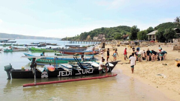 A beach with boats docked and people on the sand. - Duyung Rooms and Resto by Zuzu (Kuta)