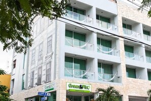 A multi-story building with a green and white facade, featuring a restaurant named "Green & Fit" on the ground floor.
