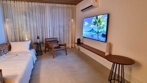 Une chambre d’hôtel avec un lit, un canapé, une télévision, une chaise et une petite table.