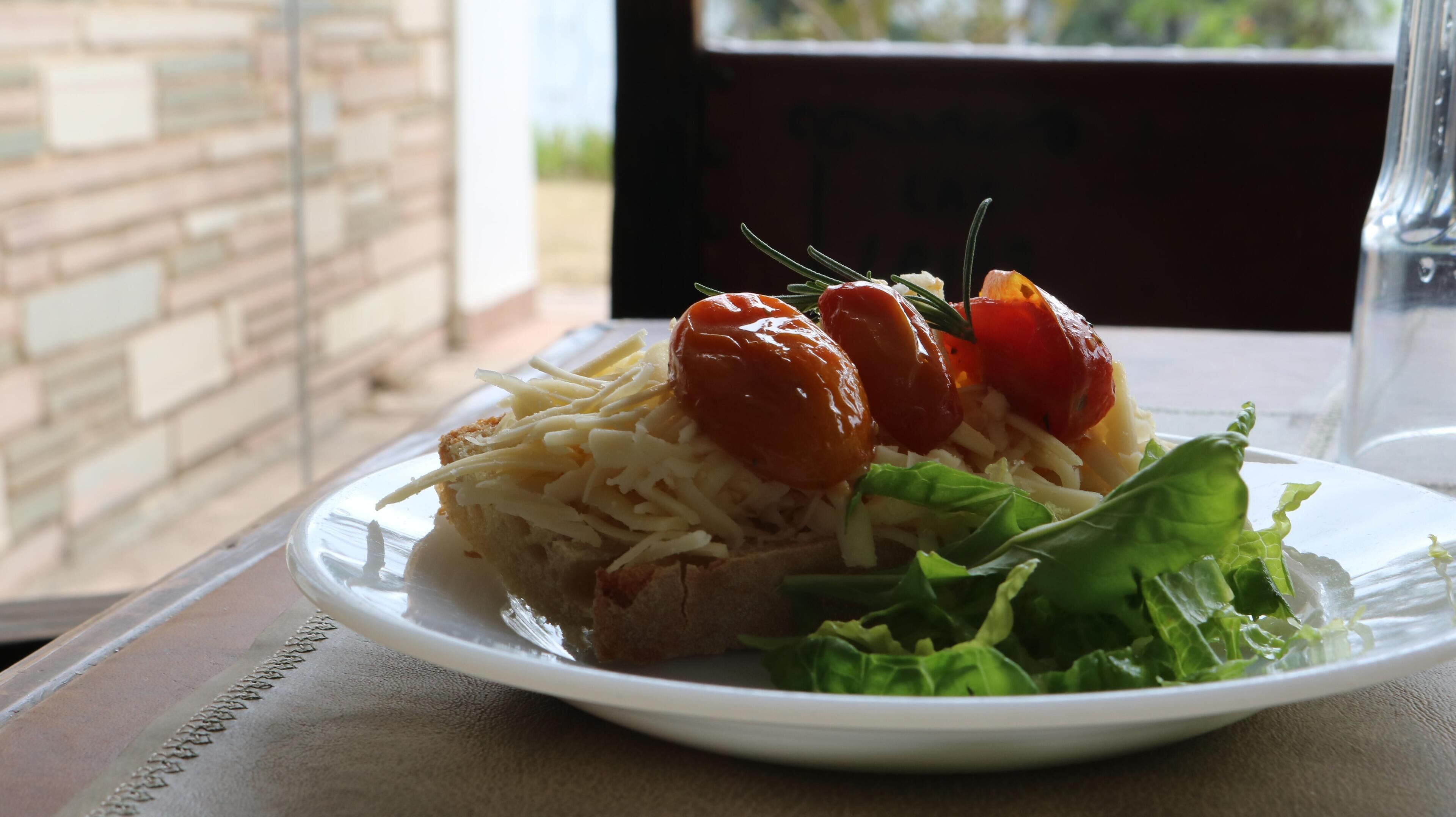 Une assiette de nourriture comprenant une tranche de viande, du fromage et des légumes, le tout présenté sur une assiette blanche.