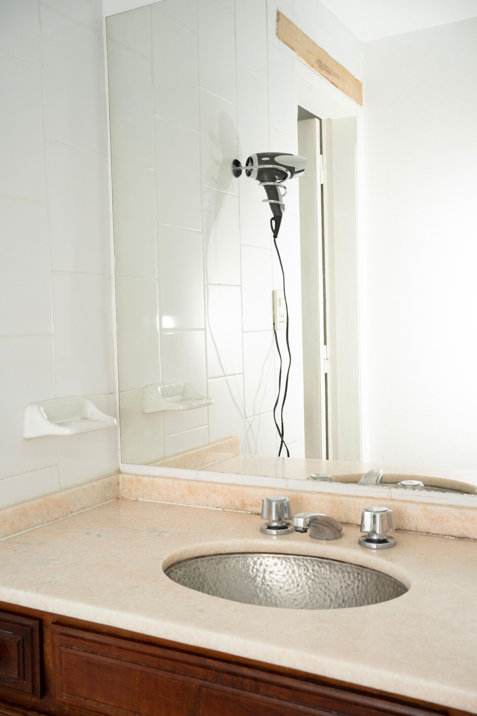 A bathroom with a sink, mirror, and hairdryer.