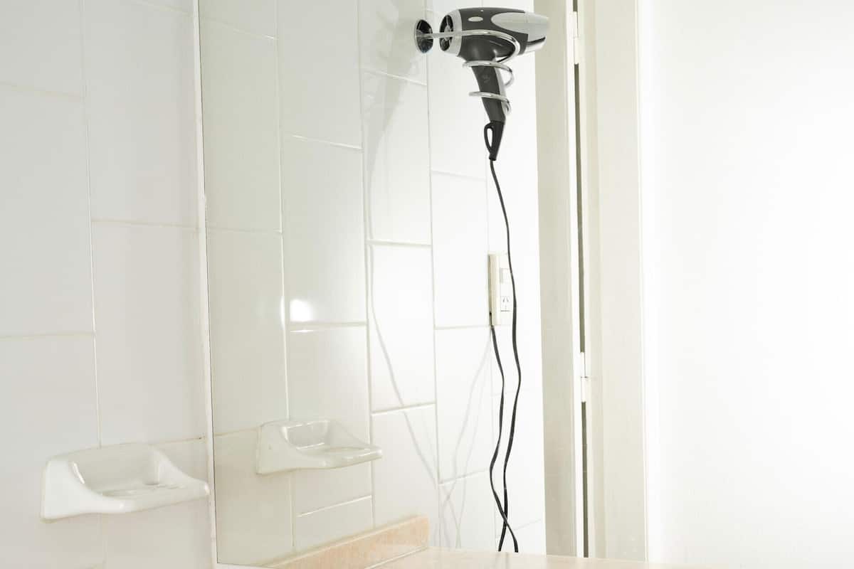A bathroom with a sink, mirror, and hairdryer.