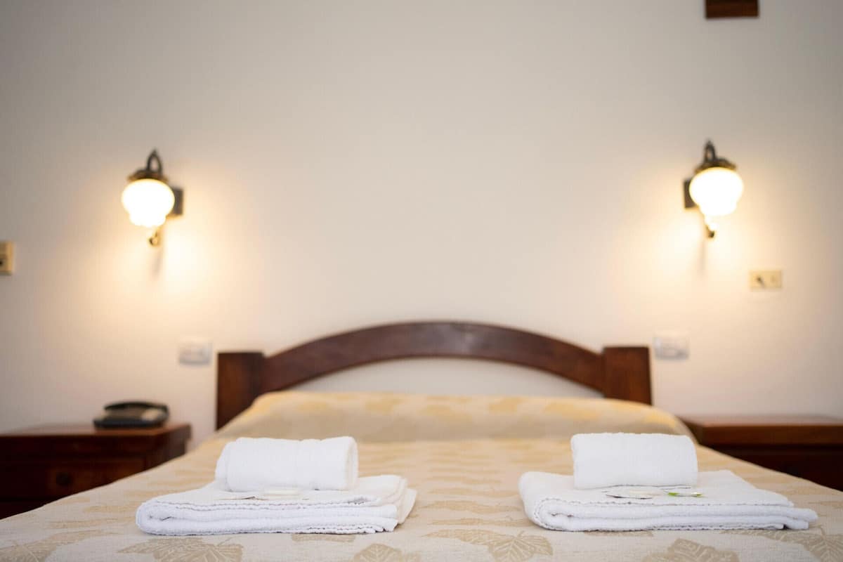 Une chambre d’hôtel avec un lit, deux lampes de chevet et deux serviettes pliées posées sur le lit.