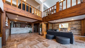 Un intérieur spacieux agrémenté d’un escalier en bois, d’un comptoir d’accueil en pierre et d’un espace détente moderne.