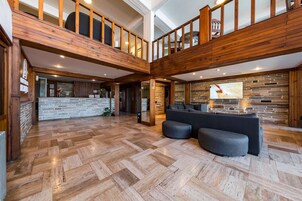 Un interior espacioso con una escalera de madera, una recepción de piedra y una zona de estar moderna.