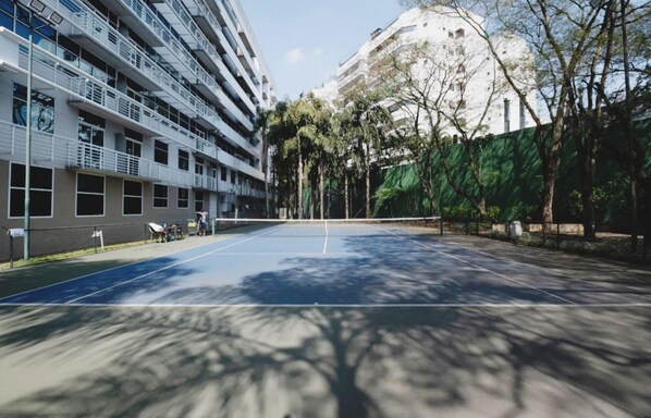 A tennis court surrounded by buildings and trees. - Flat Super Luxo Verbo Divino (São Paulo)