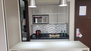 A compact kitchen with a central island, two bar stools, a microwave, and a coffee maker.