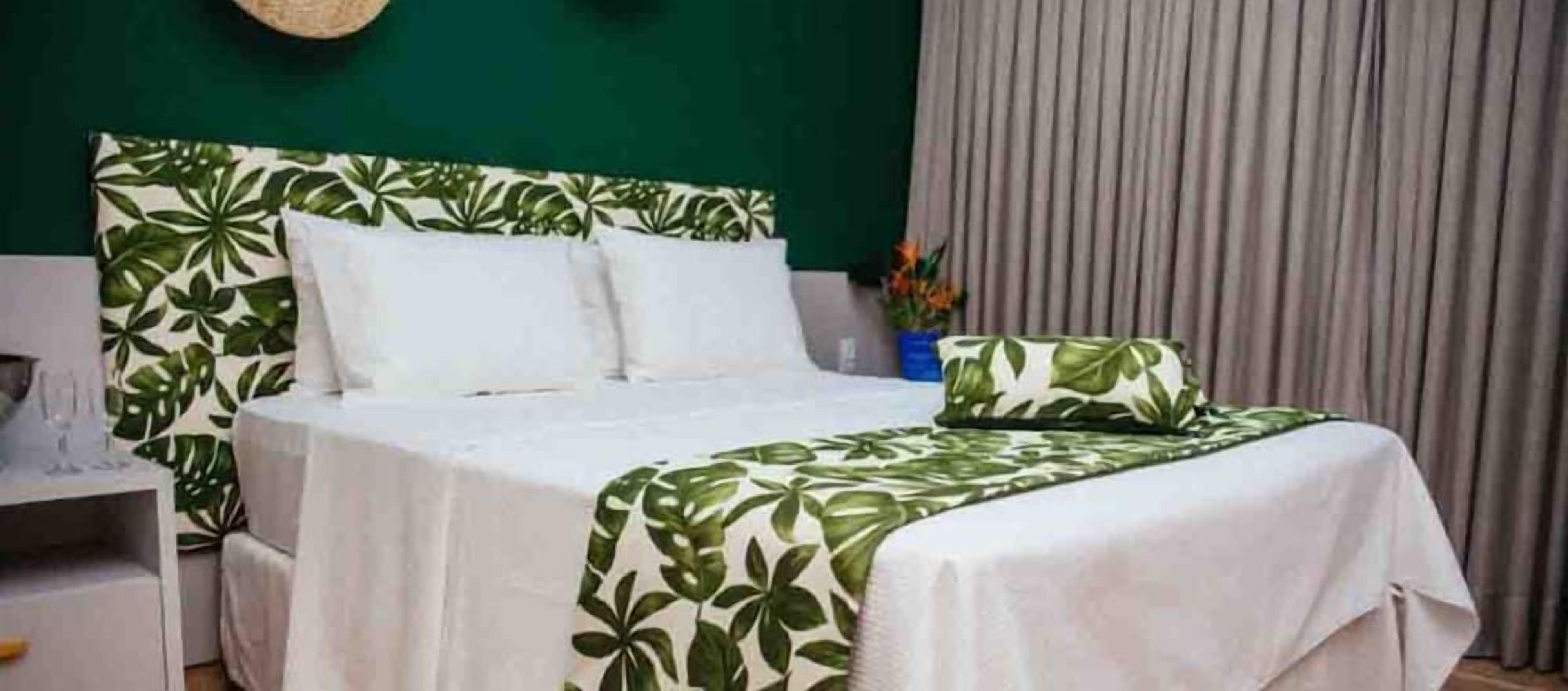 A bed with a white headboard and a green leaf-patterned bedspread.