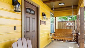 A porch with a wooden bench, a door, and a sign indicating a 'Cowboy Lodge'. - Stockyards Cowboy Lodge - 1/8 mi to Stockyards-Sleeps up to10-add 11 next door! (Fort Worth)