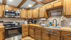 A kitchen with wooden cabinets, stainless steel appliances, a microwave, a stove, and a sink. - Stockyards Cowboy Lodge - 1/8 mi to Stockyards-Sleeps up to10-add 11 next door! (Fort Worth)