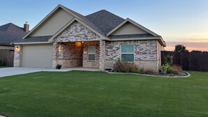 A two-story house with a stone facade, a garage, and a well-maintained lawn.