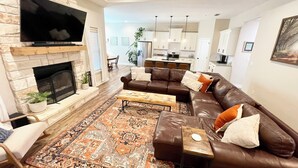A modern living room with a fireplace, leather sofa, and a large flat-screen TV.