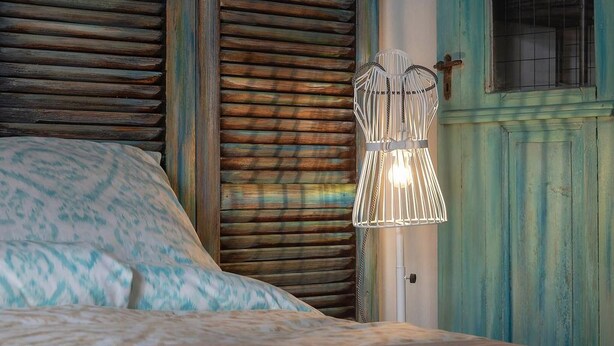 Una camera da letto con un letto, una lampada a parete e una porta con una croce.
