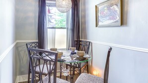 A dining area with a glass table surrounded by chairs, a hanging light fixture, and a framed picture on the wall. - Dog-Friendly Dayton Home Near Downtown + Hospitals (Dayton)