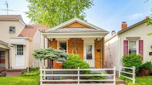 A two-story house with a front porch, a brick chimney, and a white picket fence. - Dog-Friendly Dayton Home Near Downtown + Hospitals (Dayton)