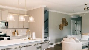A modern kitchen with a central island, bar stools, and pendant lighting. - Cozy, Clean Home for Family or Friends (Bowling Green)