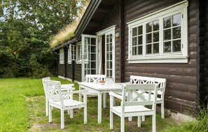 A wooden cabin with a porch, white outdoor furniture, and a grassy yard. - 3 bedroom stunning home in Gilleleje (Gilleleje)