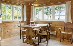 A wooden cabin with a dining table and chairs, large windows, and a hanging light fixture. - 3 bedroom stunning home in Gilleleje (Gilleleje)