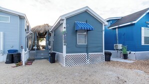 Een huis aan de kust met een rieten dak, een veranda en een klein terras.