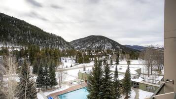 Zona residencial con piscina, telesilla y vistas a montañas nevadas.