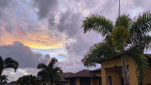 Ein Wohngebiet mit Häusern, Palmen und einem bewölkten Himmel.