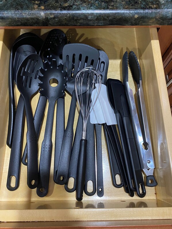Un tiroir contenant divers ustensiles de cuisine, notamment des spatules, des fouets et des pinces.