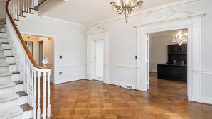 Une pièce spacieuse dotée d’un plancher en bois, de murs blancs et d’un escalier avec des balustrades blanches.