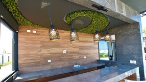 Eine moderne Küche mit Holzrückwand, Marmorarbeitsplatte und hängenden Pendelleuchten.
