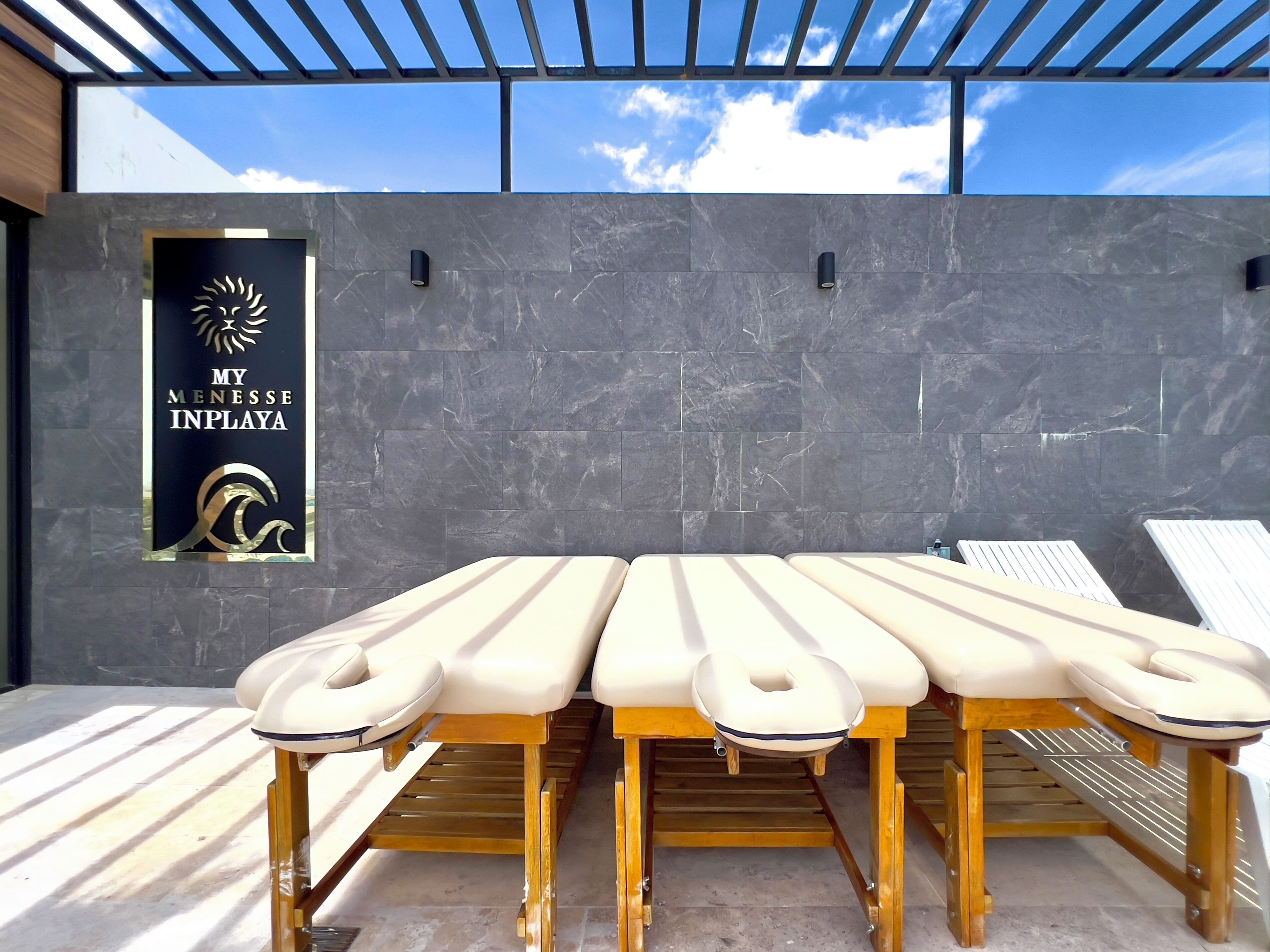 Een massagetafel met een logo, een muur met een bord en een pergola.