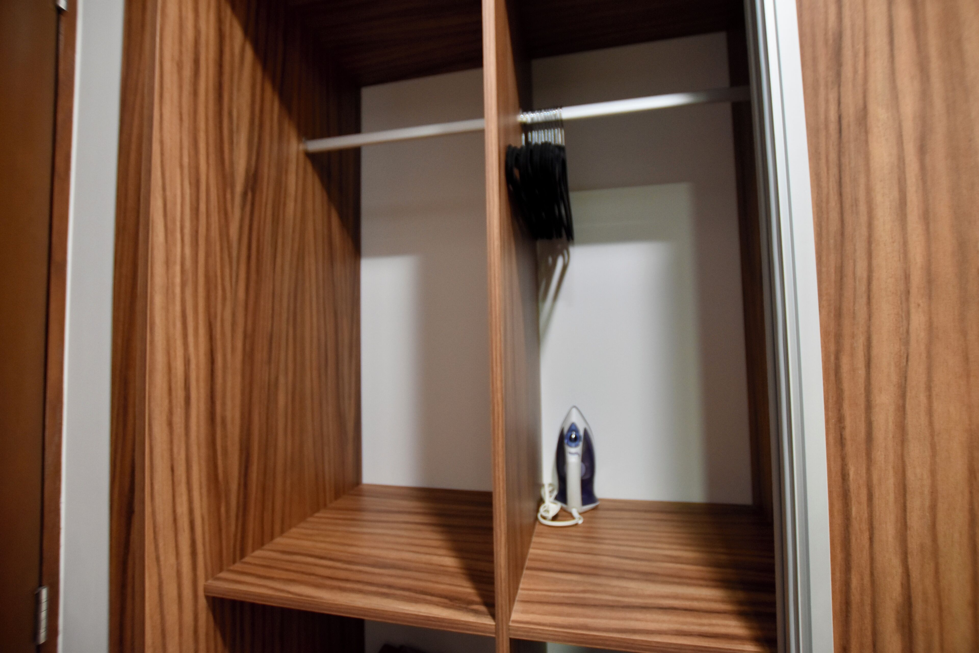 A wooden wardrobe with two shelves and a hanging rod.