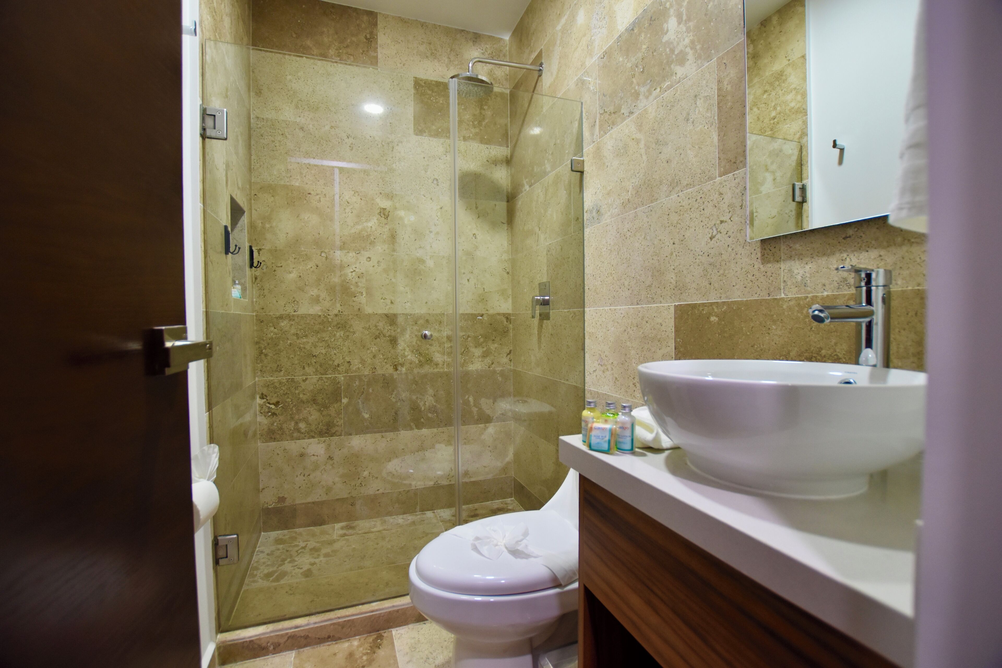 A bathroom with a glass-enclosed shower, a white sink, and a toilet.