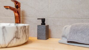 A bathroom sink with a marble basin, a copper faucet, and a soap dispenser on a wooden countertop. - HAB 2 STA MARTA (Santa Marta)