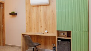 A room with a wooden desk, a chair, a small shelf with a plant, an air conditioner, and a green panel. - HAB 2 STA MARTA (Santa Marta)