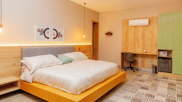 A modern bedroom with a large bed, a wooden headboard, a small desk, and a green cabinet. - HAB 2 STA MARTA (Santa Marta)
