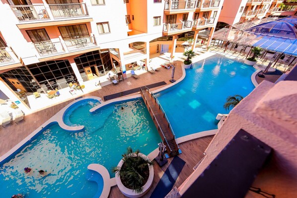A multi-level hotel with a central swimming pool, outdoor seating areas, and balconies. - Jurerê Beach Village é Destino Floripa (Florianópolis)