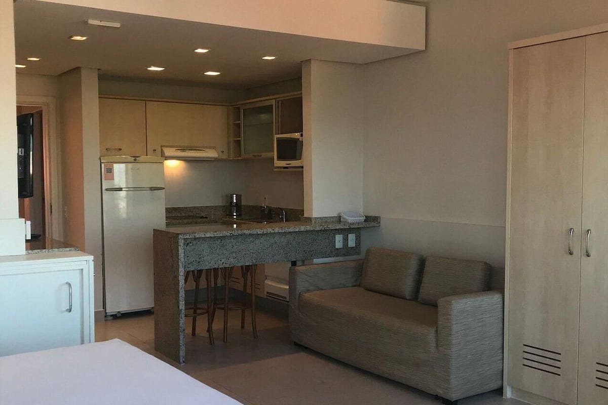 Habitación de hotel compacta con cama, kitchenette y sofá.