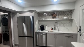A modern kitchen with stainless steel appliances, a built-in dishwasher, and a white countertop. - Oceanfront Comfort Unit#1 (Corpus Christi)