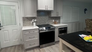 A modern kitchen with white cabinets, a black countertop, and a stainless steel oven. - Oceanfront Comfort Unit#1 (Corpus Christi)