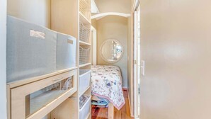 Een kleine kamer met een bed, een spiegel en inbouwopbergruimte.