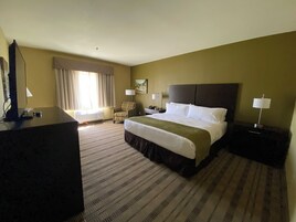 Una habitación de hotel con una cama grande, una silla, un escritorio y una lámpara.