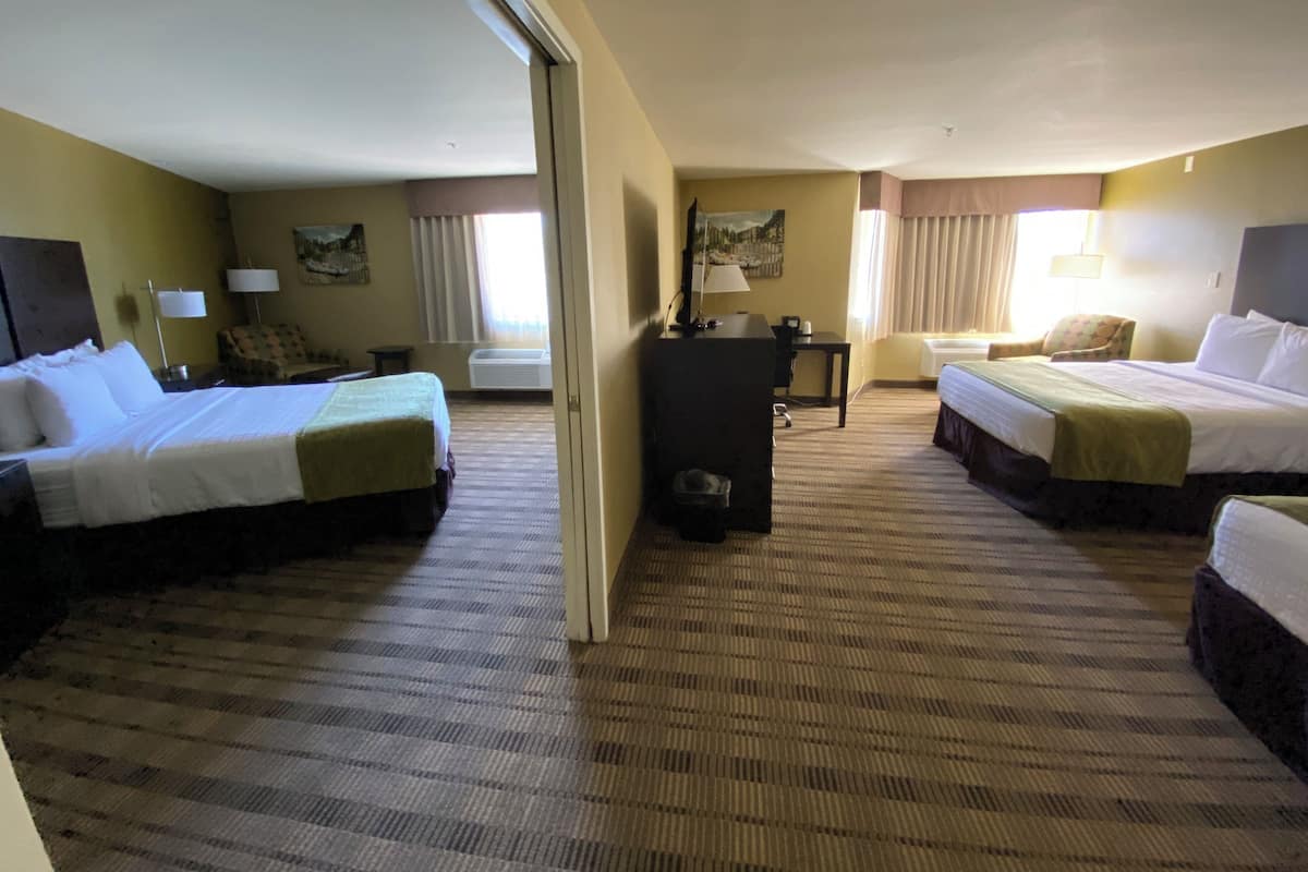 A hotel room with two beds, a desk, a chair, and a television.