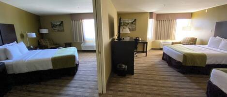 A hotel room with two beds, a desk, a chair, and a television.