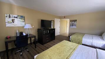 Quarto de hotel com duas camas, uma escrivaninha com computador, televisão e micro-ondas.