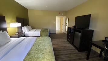 A hotel room with two beds, a desk, a television, and a carpeted floor.