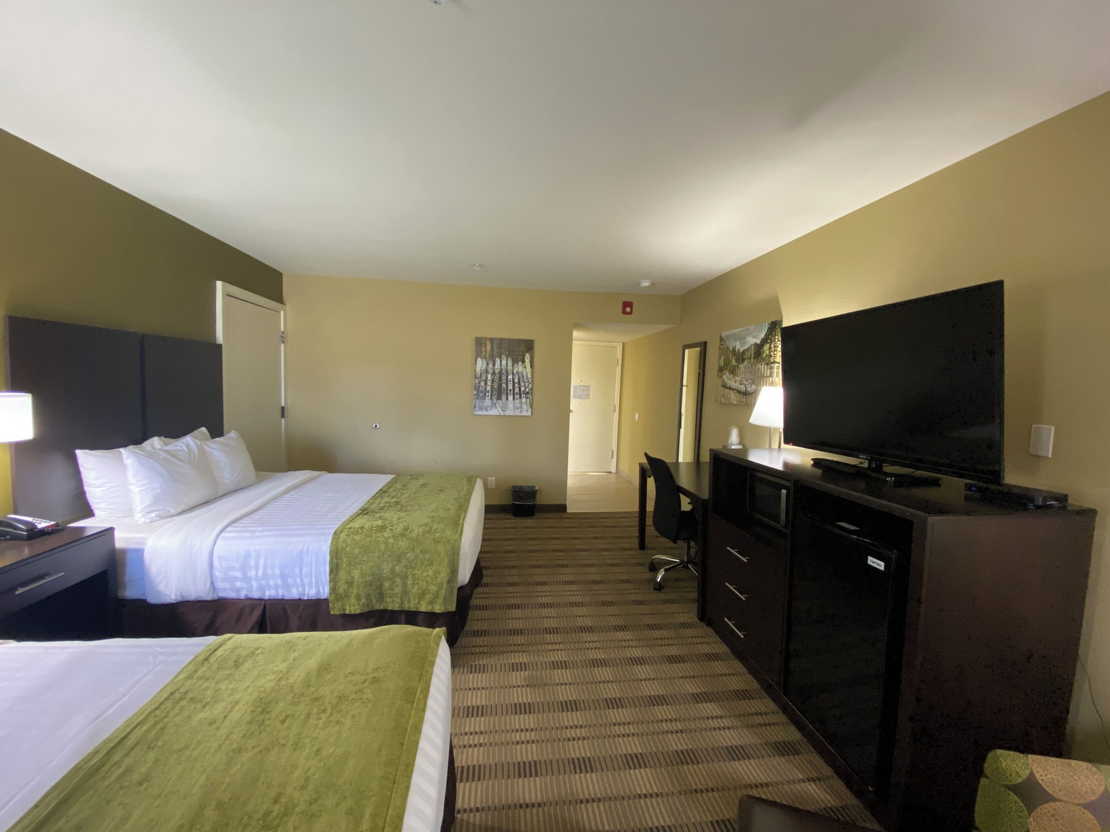 Een hotelkamer met twee bedden, een bureau met een televisie en een spiegel.