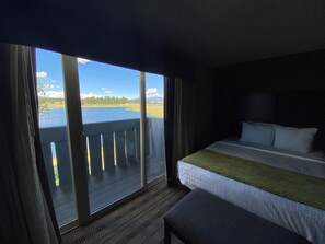 A hotel room with a large window overlooking a body of water, a bed, and a small seating area. - Pagosa Lodge (Pagosa Springs)