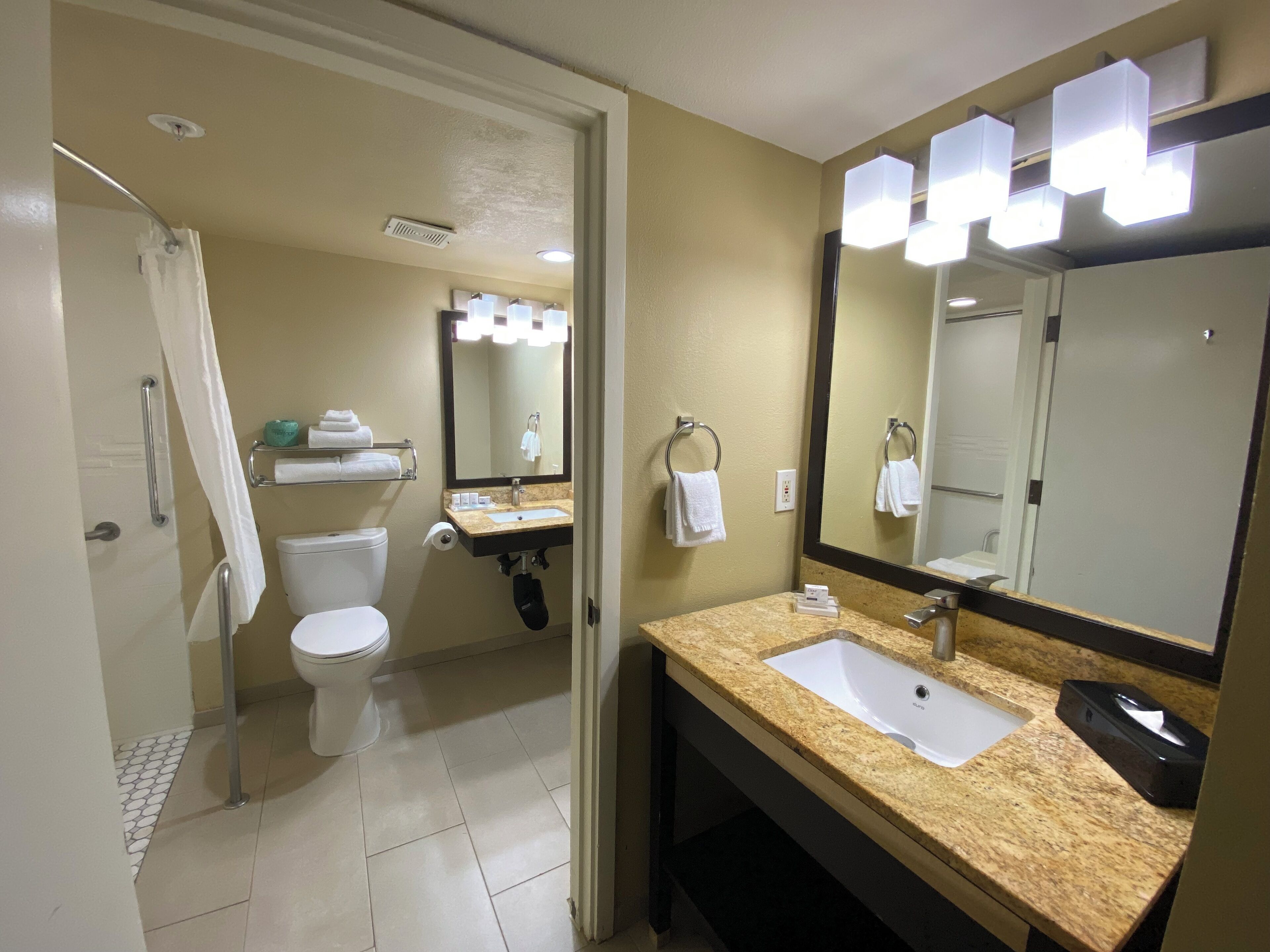 A bathroom with a toilet, sink, and mirror.